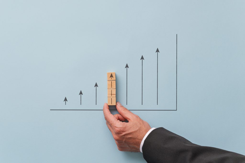 Gráfico de previsão de crescimento da economia empresarial - empresário fazendo um gráfico com setas apontando para cima. Sobre fundo azul.