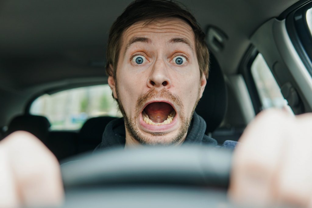 foto de um motorista masculino chocado, com expressão de surpresa e boca aberta.