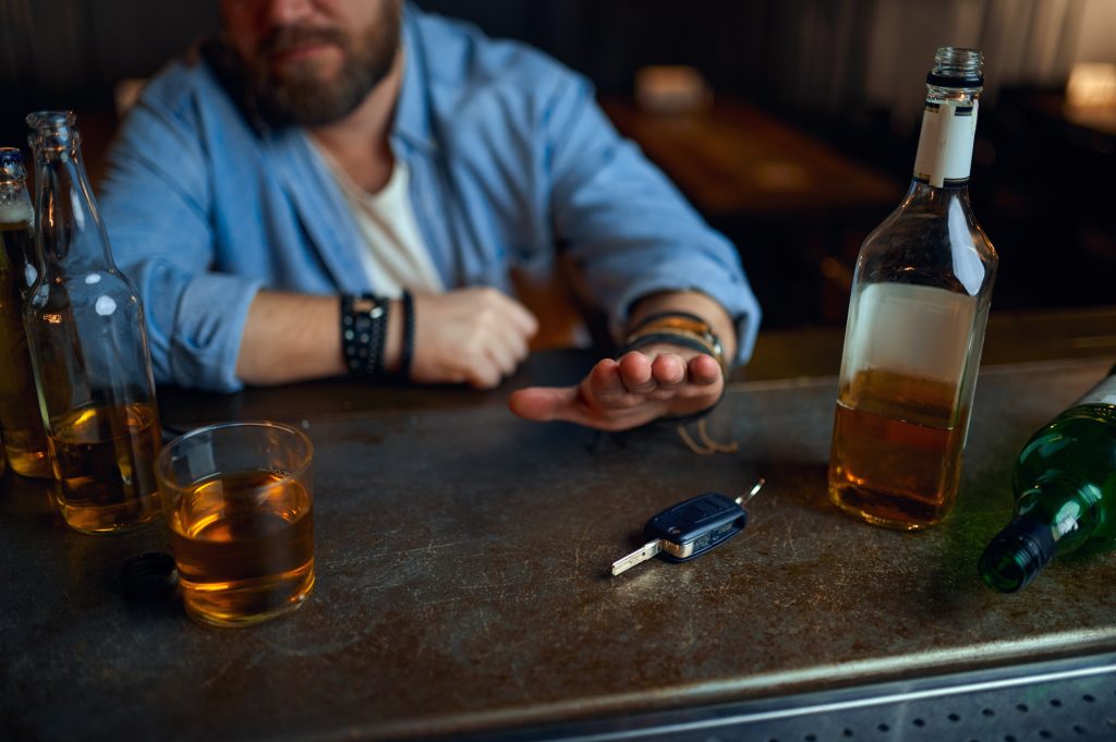 Homem bêbado se recusa a dirigir sob a influência de álcool no balcão do bar.