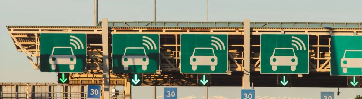 Pórtico de pedágio com placas verdes de pagamento eletrônico sobre cada faixa, com o ícone de carro e ondas de sinal